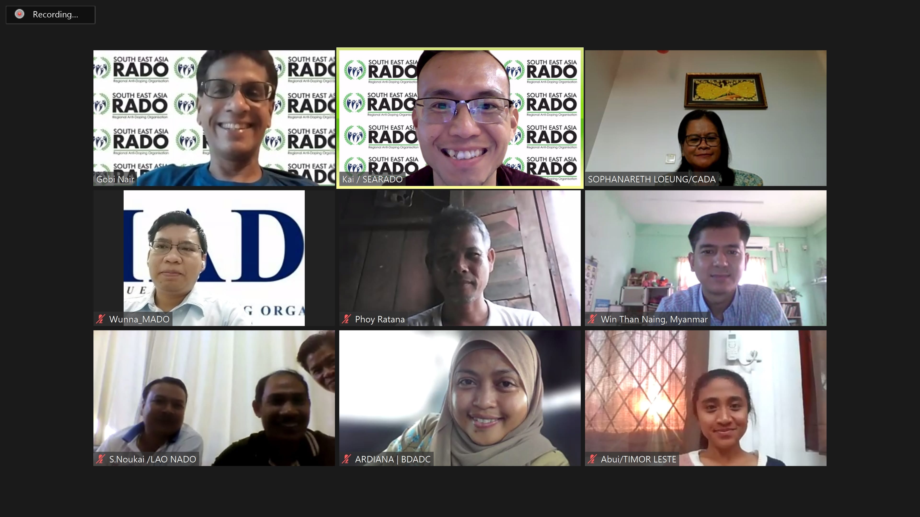 A video call with nine participants, several shown against South East Asia RADO virtual backgrounds, with name labels visible.